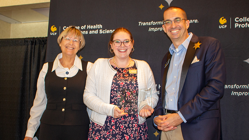 Terri Daly, Kaileigh Anne Tayek, and Matthew Theriot smiling in front of a CHPS backdrop with Kaileigh holding her award