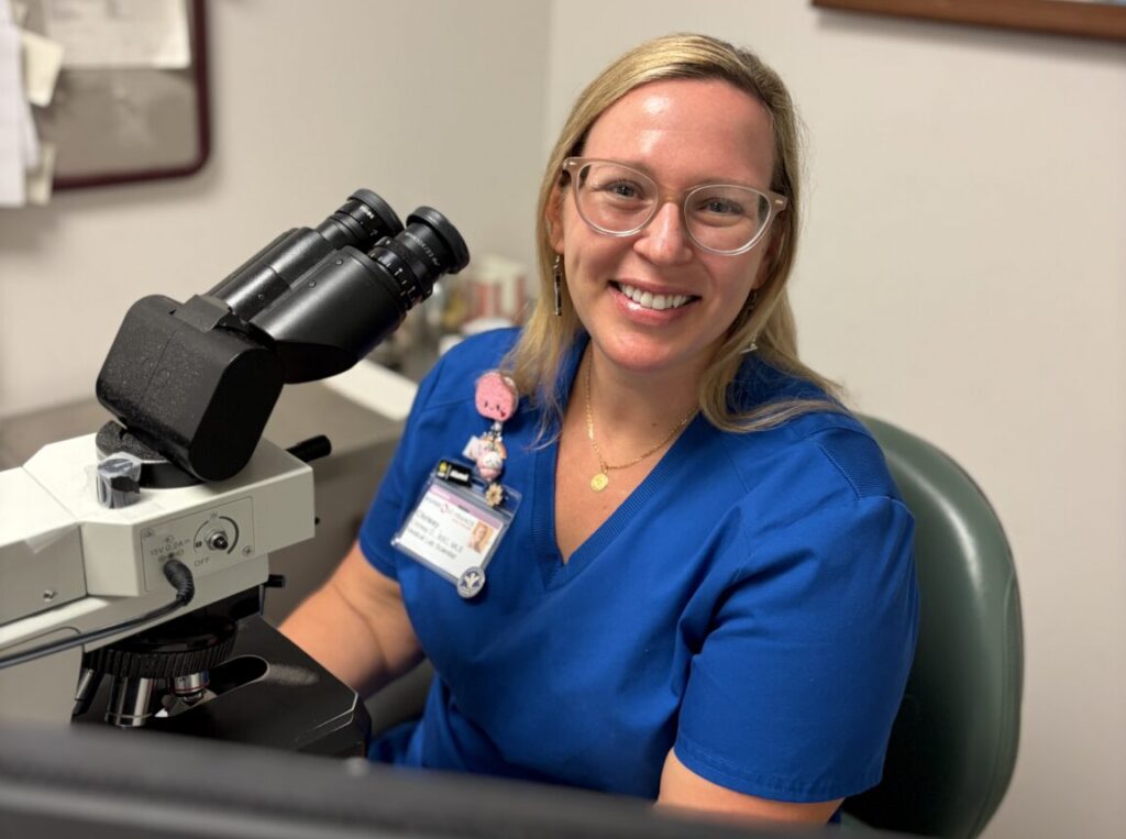 Chrissy Fidelus smiles while sitting in front of a mircroscope